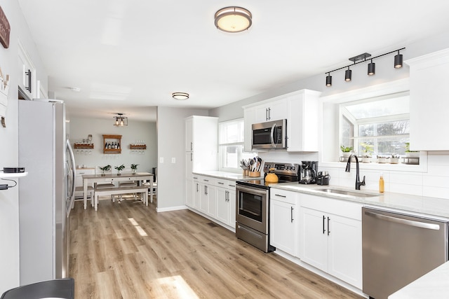 kitchen with light wood-style flooring, stainless steel appliances, a sink, and light countertops