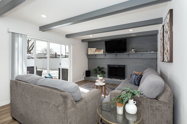 living area featuring a fireplace, baseboards, beam ceiling, and wood finished floors