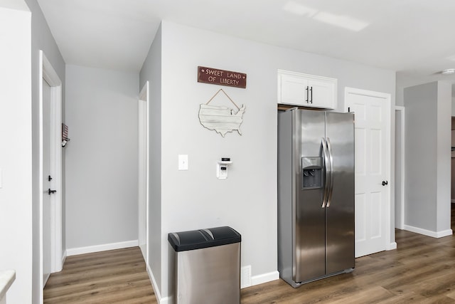 kitchen featuring stainless steel fridge with ice dispenser, visible vents, white cabinets, wood finished floors, and baseboards