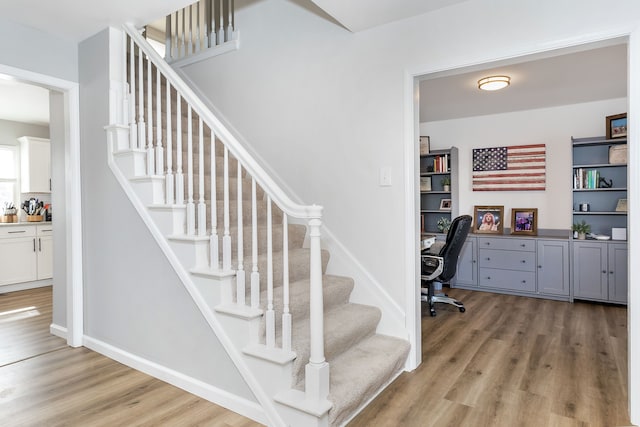 stairway with built in study area, baseboards, and wood finished floors