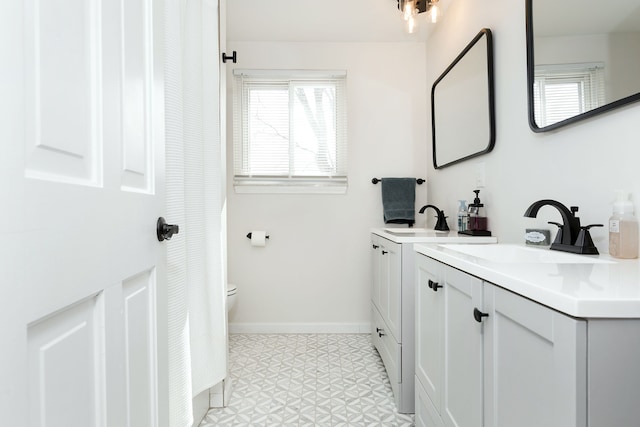 full bath with tile patterned floors, two vanities, a sink, and baseboards