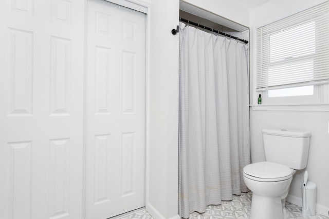 bathroom with curtained shower, toilet, and baseboards