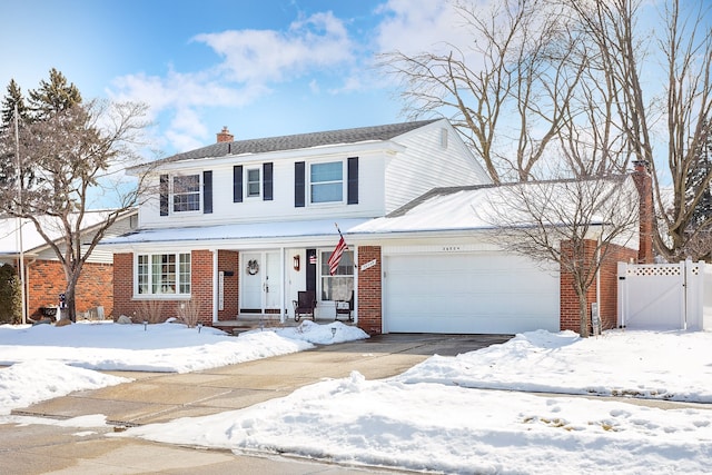 traditional-style house with a chimney, an attached garage, a gate, fence, and brick siding