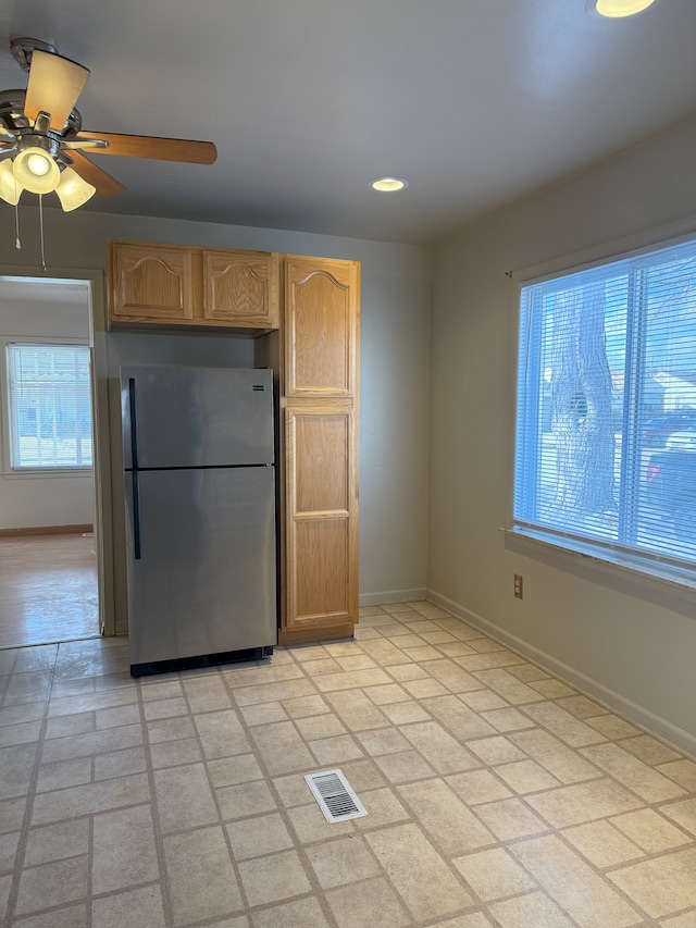 kitchen with ceiling fan, light brown cabinetry, and stainless steel fridge