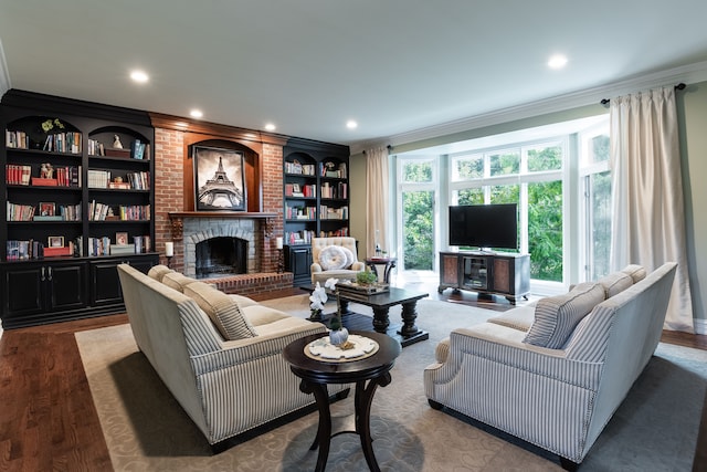 living room featuring hardwood / wood-style flooring, ornamental molding, a brick fireplace, and built in features