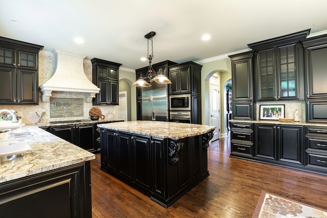 kitchen with hanging light fixtures, a center island, built in appliances, sink, and custom exhaust hood