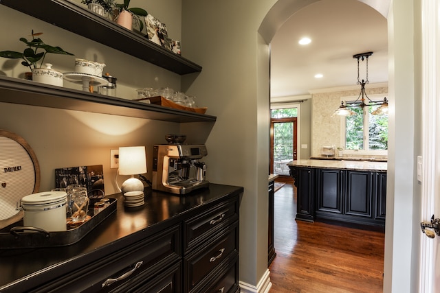 bar with dark hardwood / wood-style flooring, ornamental molding, and decorative light fixtures