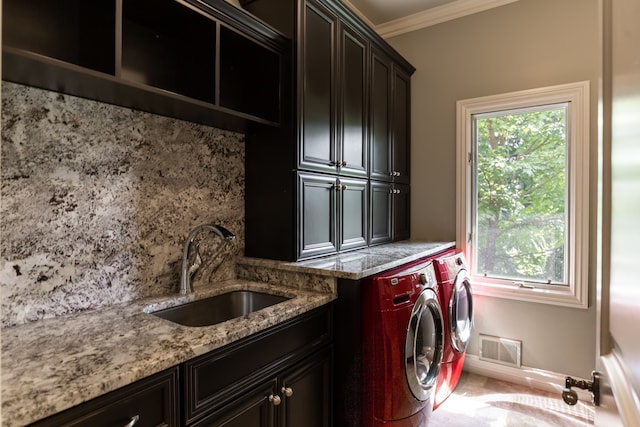 washroom featuring ornamental molding, sink, washer and clothes dryer, and cabinets