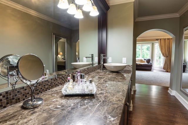 bathroom featuring decorative backsplash, vanity, crown molding, and wood-type flooring