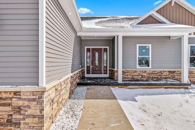 snow covered property entrance featuring a porch