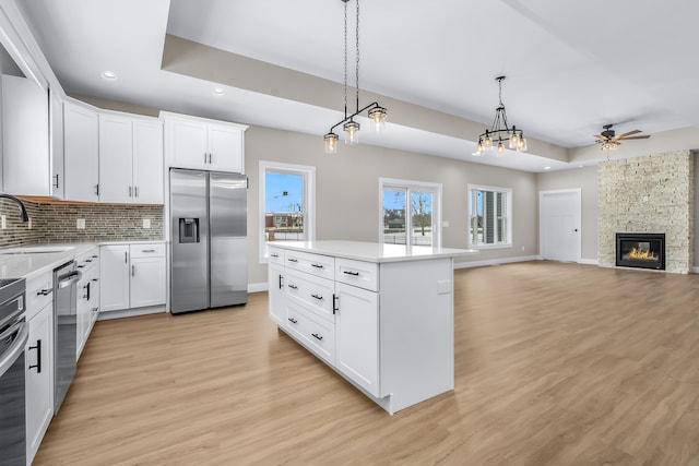 kitchen featuring a kitchen island, appliances with stainless steel finishes, white cabinets, and hanging light fixtures