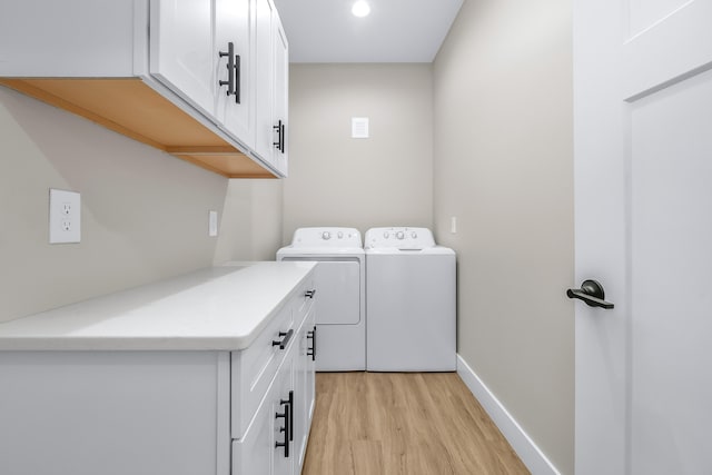 laundry area with cabinets, washer and dryer, and light wood-type flooring