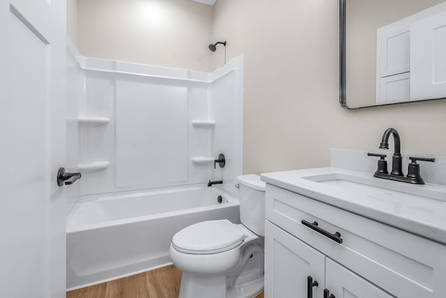 full bathroom with washtub / shower combination, toilet, hardwood / wood-style flooring, and vanity