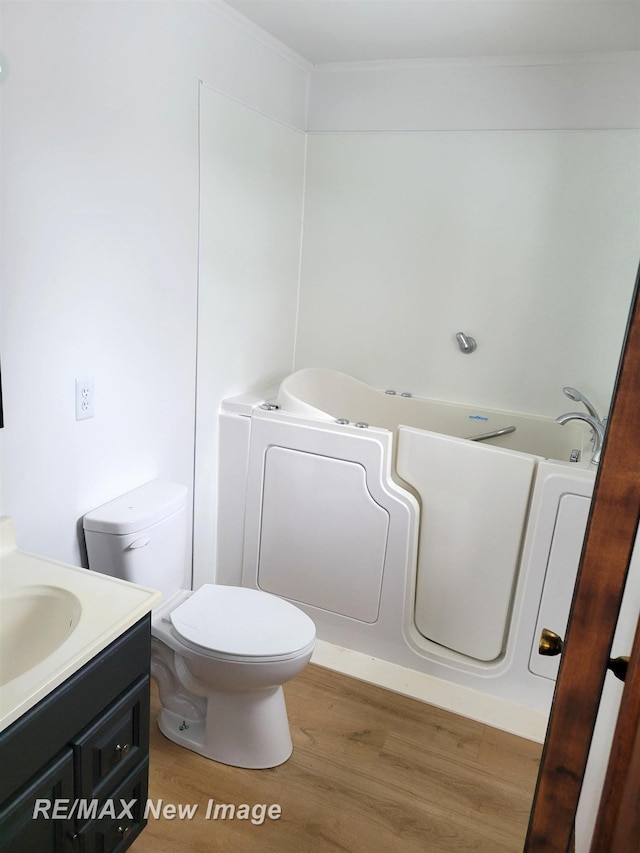 bathroom featuring a bathtub, ornamental molding, toilet, vanity, and hardwood / wood-style floors