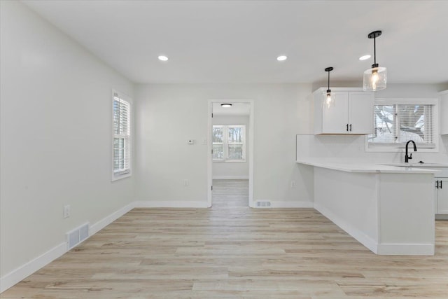 kitchen with sink, white cabinets, a healthy amount of sunlight, and pendant lighting