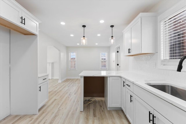 kitchen featuring decorative light fixtures, sink, white cabinets, and light hardwood / wood-style flooring