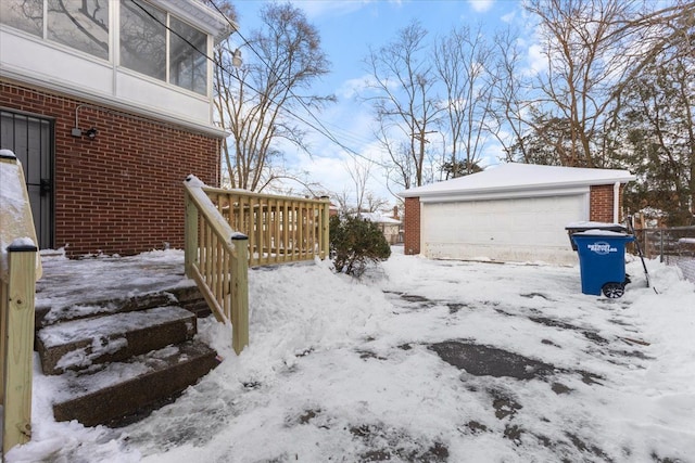 yard layered in snow featuring a garage and an outdoor structure