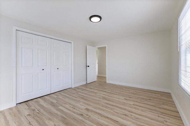 unfurnished bedroom featuring light wood-type flooring and a closet