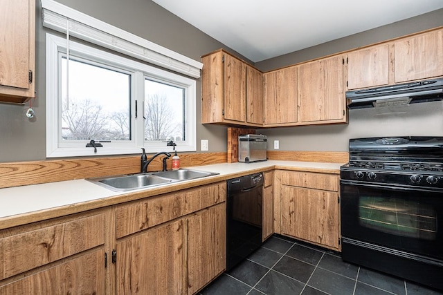 kitchen with dark tile patterned flooring, under cabinet range hood, light countertops, black appliances, and a sink