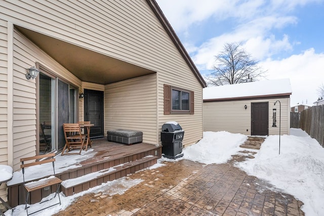 exterior space featuring a grill, fence, a deck, and an outbuilding