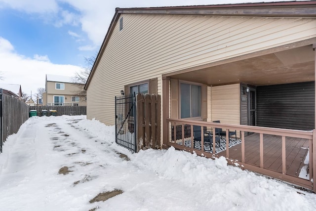 view of snow covered exterior featuring fence and a deck