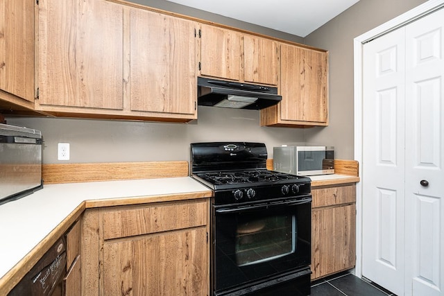 kitchen featuring dark tile patterned flooring, under cabinet range hood, light countertops, and black gas range