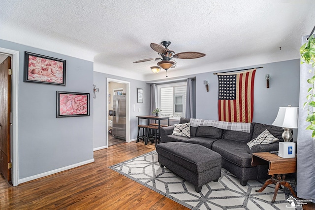 living room featuring hardwood / wood-style flooring, ceiling fan, and a textured ceiling