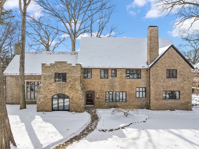 snow covered house with brick siding and a chimney