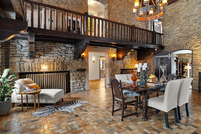 dining room with brick floor, arched walkways, a notable chandelier, and a high ceiling