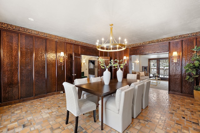 dining space with arched walkways, wooden walls, brick floor, and an inviting chandelier