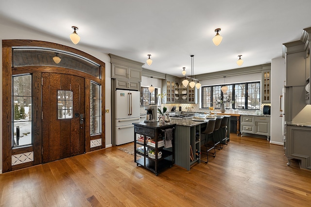 kitchen featuring glass insert cabinets, high end white refrigerator, gray cabinets, and a kitchen island