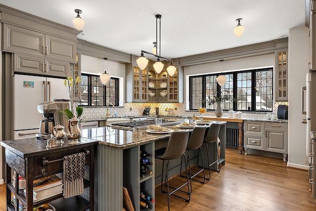 kitchen featuring glass insert cabinets, dark stone counters, high end white refrigerator, and dark wood finished floors