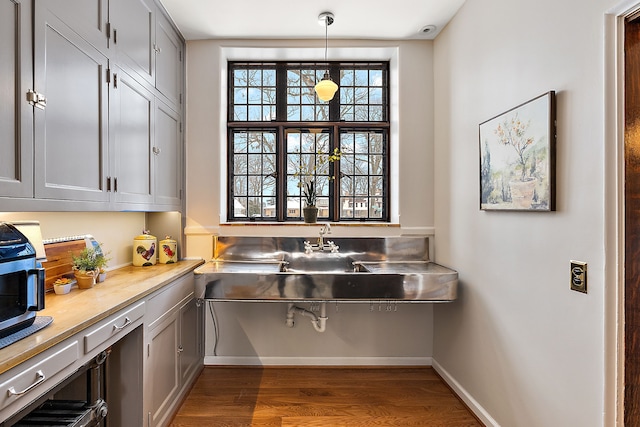 interior space with dark wood-style flooring, light countertops, hanging light fixtures, gray cabinetry, and baseboards