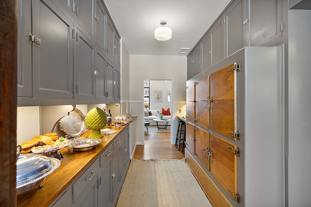 kitchen with butcher block counters, visible vents, light wood finished floors, and gray cabinetry