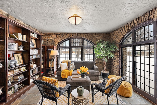 sitting room with a textured ceiling and stone tile floors