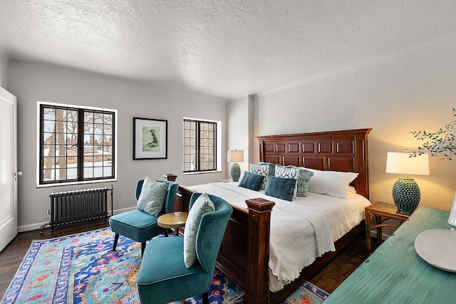 bedroom featuring dark wood-style floors, a textured wall, radiator heating unit, and a textured ceiling