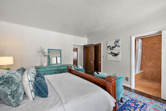 bedroom featuring connected bathroom, a textured ceiling, dark wood-style flooring, and a textured wall