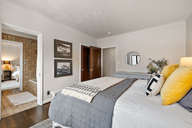 bedroom with ensuite bath, baseboards, dark wood finished floors, and a textured ceiling