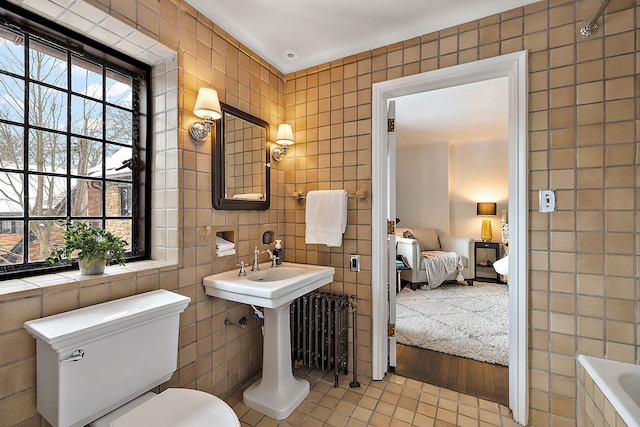 bathroom featuring tiled tub, a healthy amount of sunlight, and tile walls