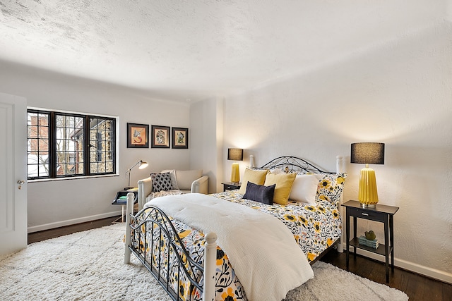 bedroom with a textured ceiling, dark wood finished floors, and baseboards