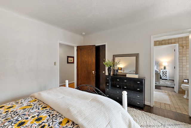 bedroom featuring dark wood-type flooring, a closet, a textured ceiling, and baseboards