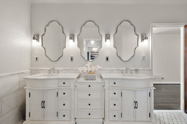 full bathroom with double vanity, wood finished floors, wainscoting, and a sink