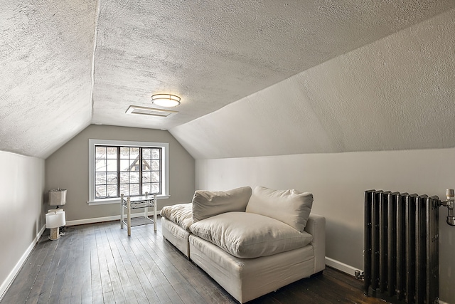 living area featuring lofted ceiling, dark wood-style flooring, baseboards, and radiator