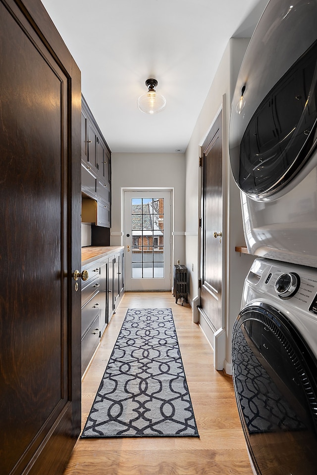 laundry room featuring stacked washer and dryer, light wood-type flooring, and laundry area