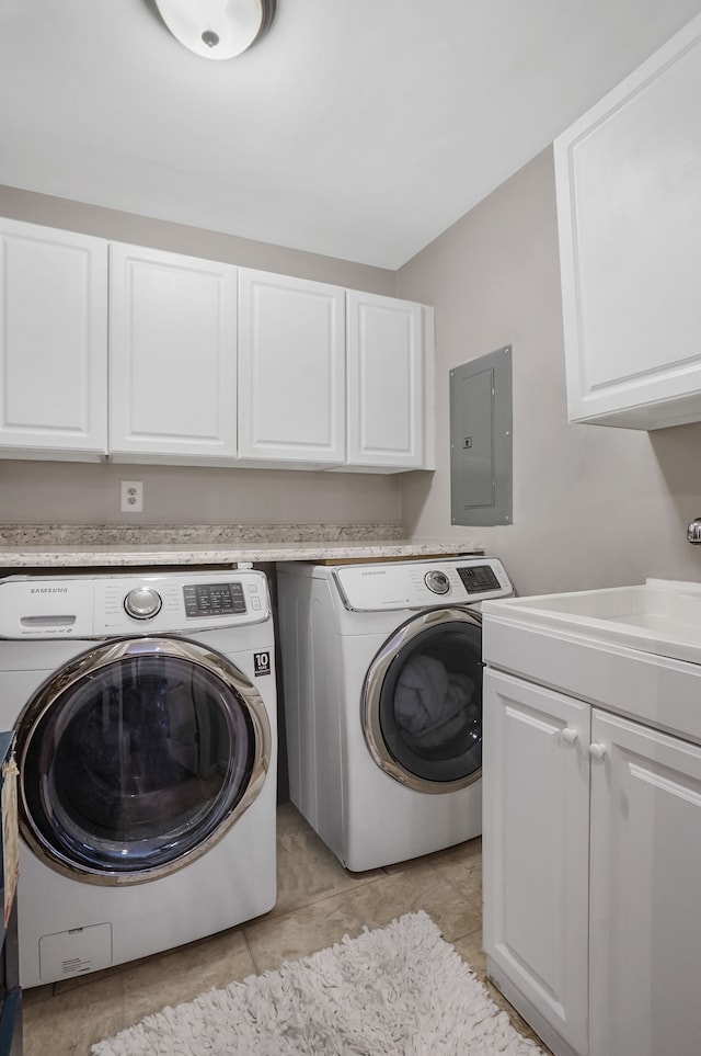 clothes washing area featuring sink, electric panel, light tile patterned floors, washer and dryer, and cabinets