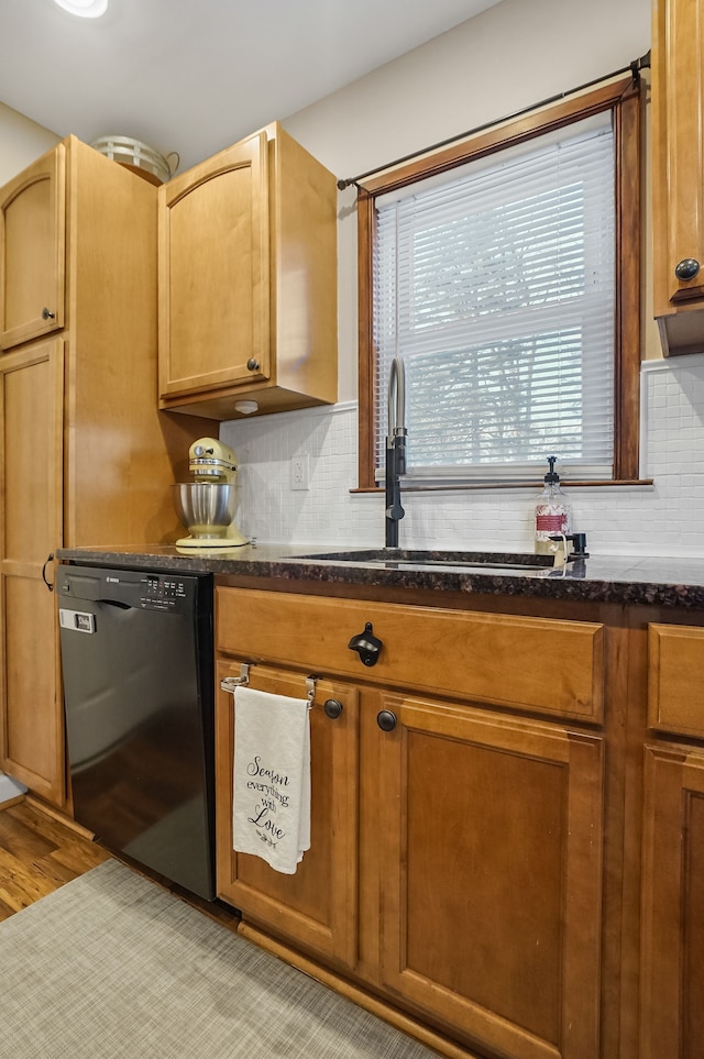 kitchen featuring sink, dark stone countertops, black dishwasher, and tasteful backsplash