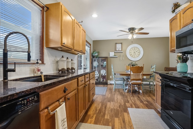 kitchen with dark stone counters, sink, black appliances, and backsplash