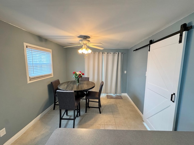 tiled dining space featuring ceiling fan and a barn door