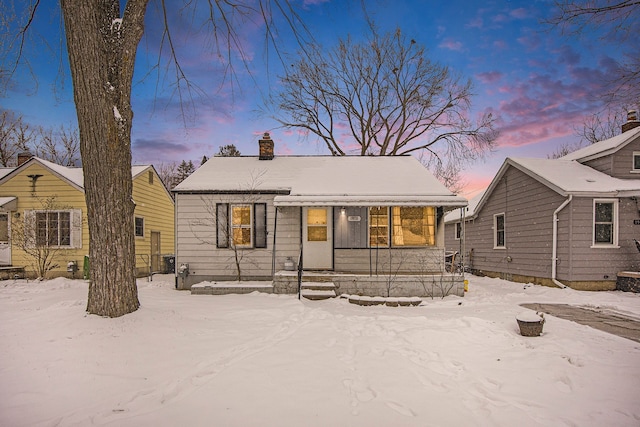 snow covered rear of property featuring covered porch