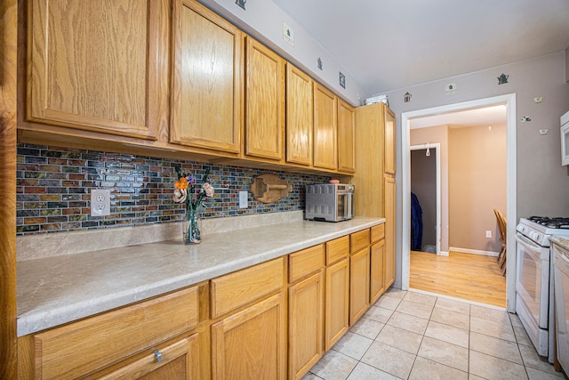 kitchen with light tile patterned flooring, decorative backsplash, and gas range gas stove